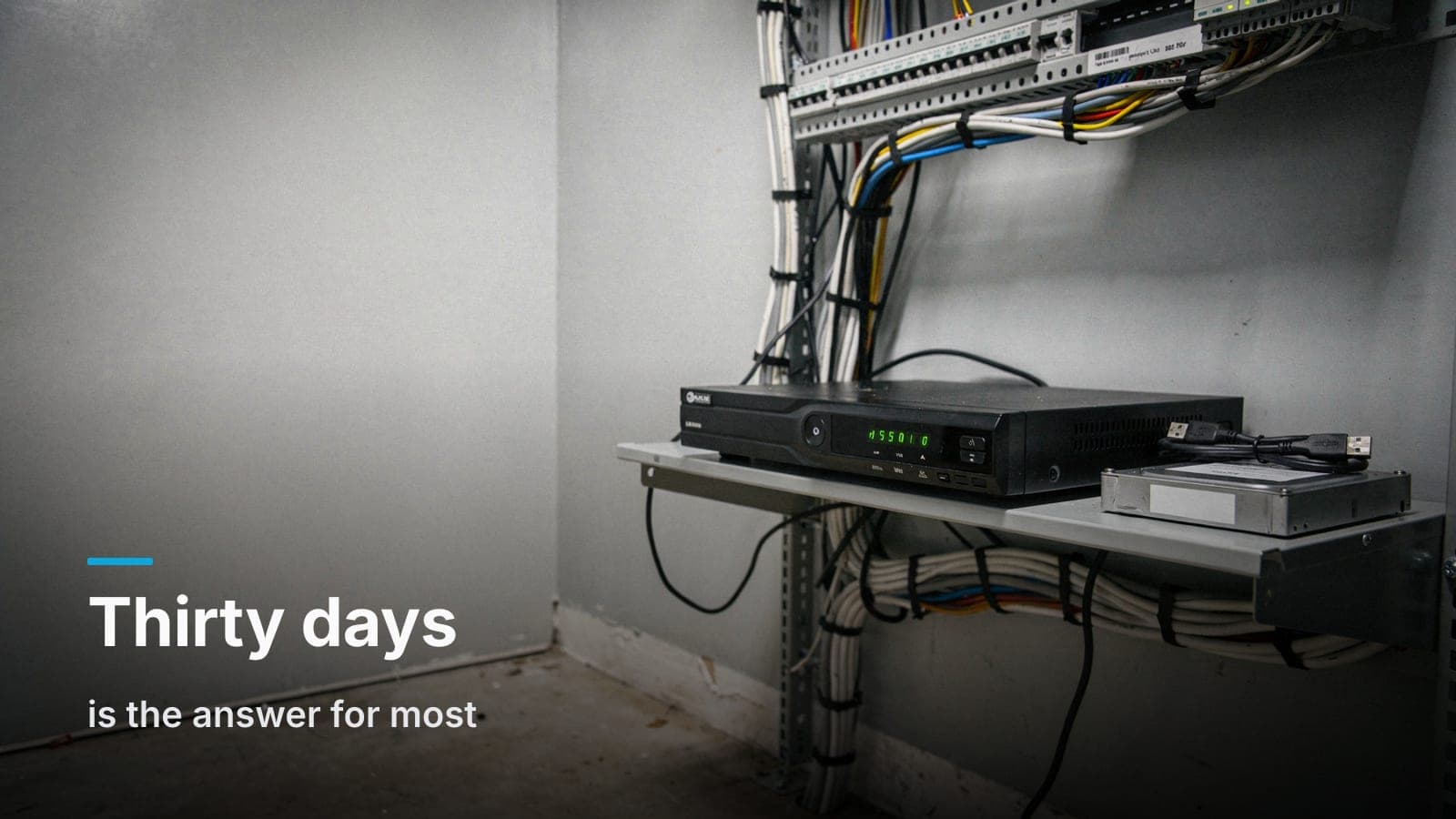 A network video recorder with steady drive lights on an IT closet shelf, next to a labeled external hard drive ready for footage export