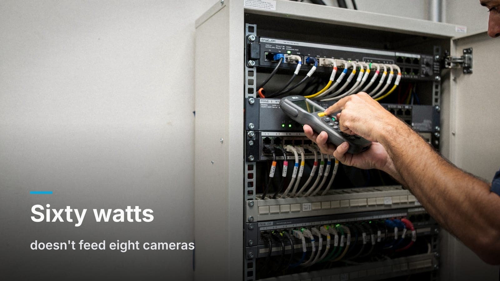 A technician's hand holds a cable tester to a dark port on a rack-mounted PoE switch in an open network cabinet