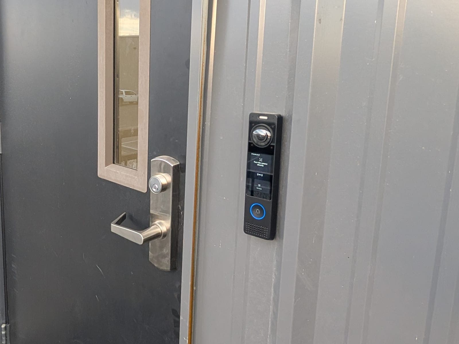 UniFi Access reader installed beside a steel exterior door with a lever handle